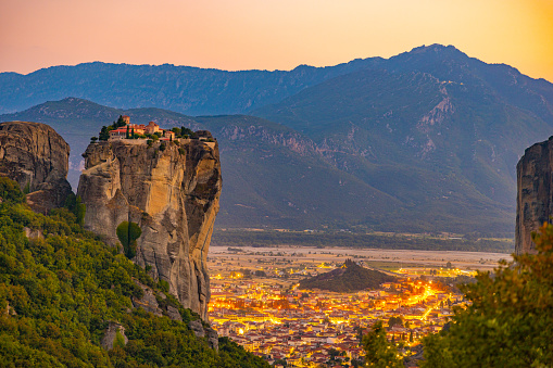 Beautiful view of Meteora monastery and illuminated cityscape against mountains during sunset