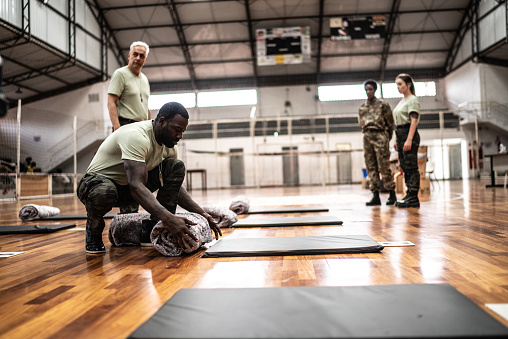 Soldiers placing mats and blankets on the floor at a gymnasium
