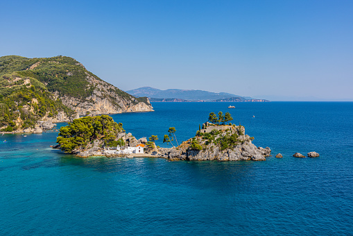Scenic view of old church at island amidst seascape against clear blue sky during summer