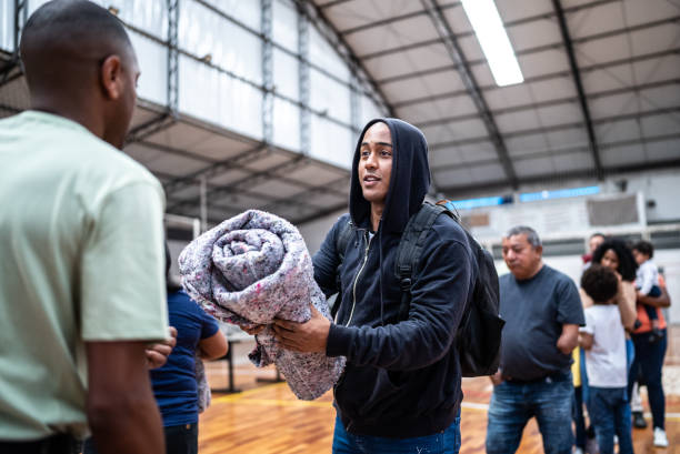 jovem recebendo um cobertor de um soldado em um ginásio - volunteer charity and relief work group of people people - fotografias e filmes do acervo