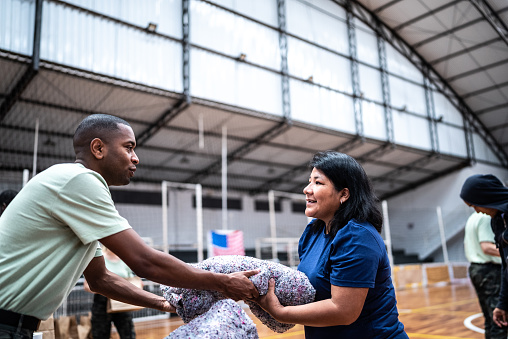 Mature woman receiving a blanket from a soldier at a gymnasium