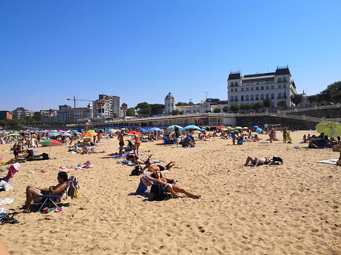 People enjoying sunbathing at Playa Sardinero in Santander, the capital of the autonomous community and historical region of Cantabria situated on the north coast of Spain.