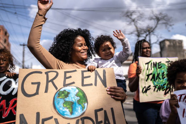 A young girl stands in front of a landfill holding a cardboard sign that reads Stop Pollution, calling attention to environmental issues and the need for cleaner habits.