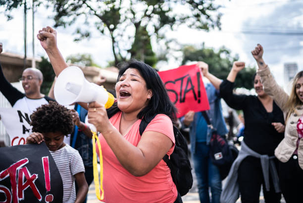 Mature woman talking in a megaphone during a protest in the street Mature woman talking in a megaphone during a protest in the street activist speech stock pictures, royalty-free photos & images