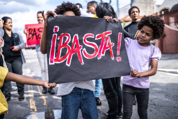 istock Group of people protesting in the streets holding stop sign (in Spanish) 1432213263