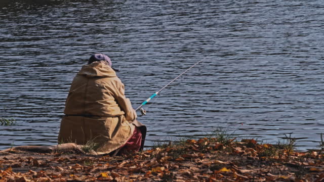Elderly Woman is Fishing in a Pond in the Fall