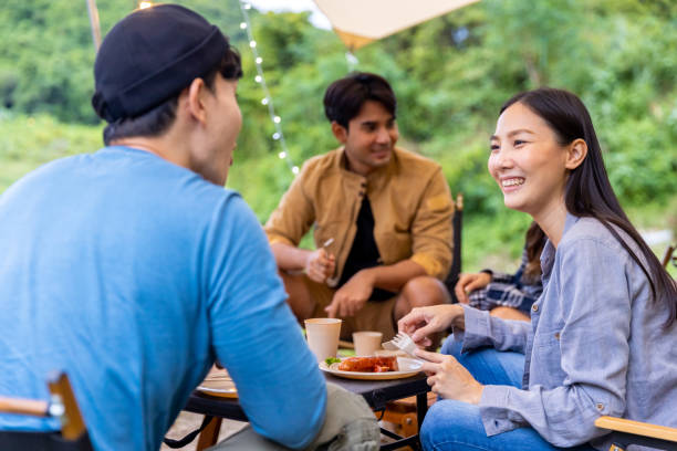 istock Group of Asian people cooking and having dinner while camping together at summer sunset. 1432215790