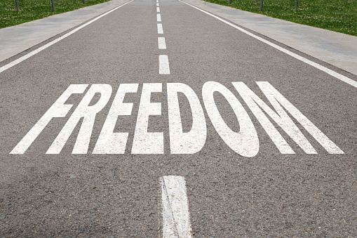 Freedom word written on asphalt road