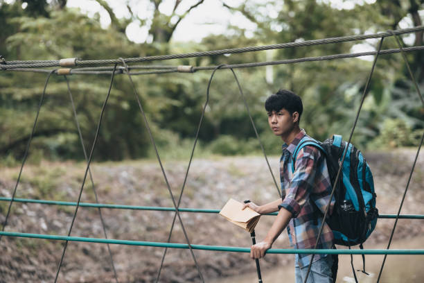 istock Hikers use trekking pole with backpacks and hold map walking through the bridge in the forest. hiking and adventure concept. 1432219187