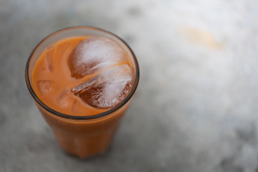 Orange iced condensed Thai milk tea in transparent glass. Close up