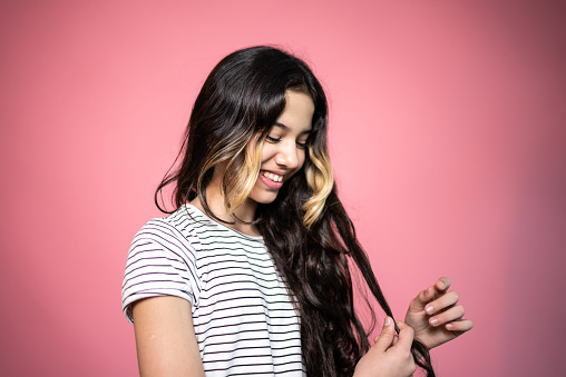 Teenager smiling while looking to her hair