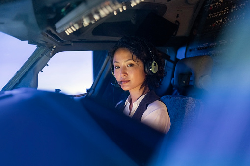 Portrait of a female trainee pilot sitting inside a flight simulator