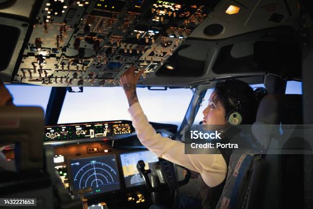 Rear View Of A Woman Pilot Adjusting Switches While Flying Airplane Stock Photo - Download Image Now