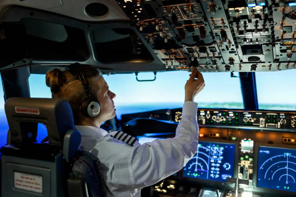 pilota che aziona gli interruttori mentre pilota un moderno jet aereo - piloting foto e immagini stock