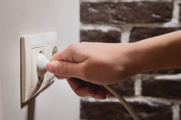 istock A young woman inserts a plug into a socket. A young woman plugs a charger or electrical appliance power cord into a socket. High quality photo 1432222709