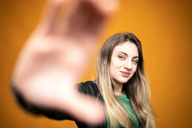 Photo of Portrait of a teenage girl gesturing on an orange background