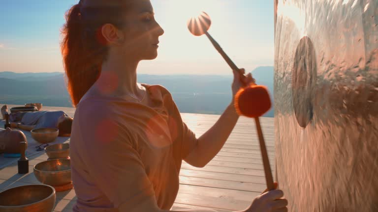 CS Woman playing a gong on the mountain top in a sound therapy session