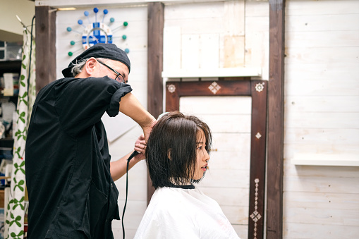 Hairdresser drying customer's hair in hair salon