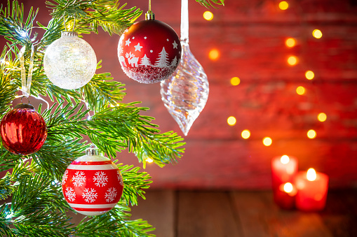 Christmas fir tree background with baubles, snowflake and glowing Christmas lights bokeh