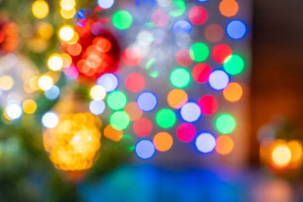 Blurred Christmas fir tree background with baubles, snowflake and glowing Christmas lights bokeh