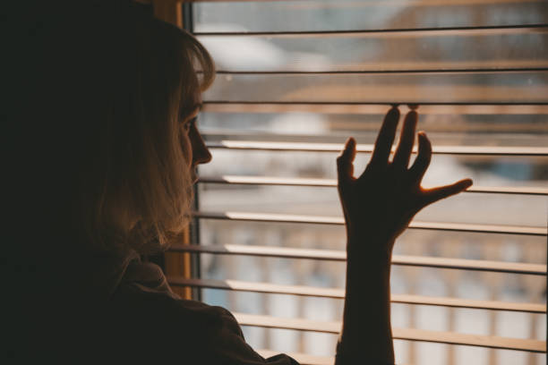 istock A woman looks out the window through the blinds 1432244800
