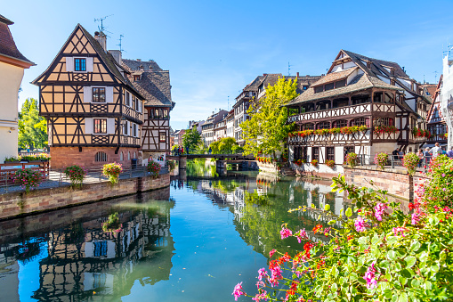 Picturesque half timbered buildings of shops, homes and cafes in the Petite France canal zone along the Ill river in the historic city of Strasbourg, in the Alsace region of France. The Maison des Tanneurs (tanners house) viewable on the riverbank