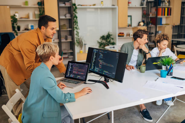 istock A woman is learning coding, a male colleague helps her with that. Codes are visible on the screens 1432248749