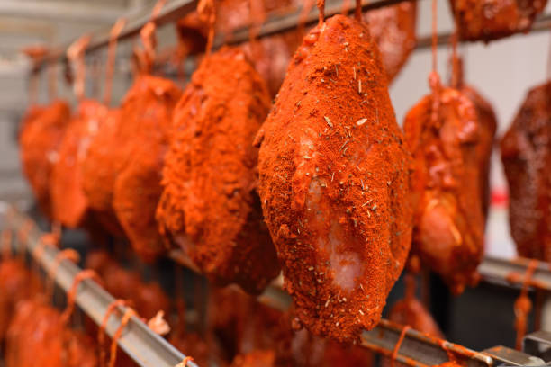 pieces of pork delicacies in paprika and spices are hung on a metal rack in a meat-packing plant or butcher's shop. stock photo