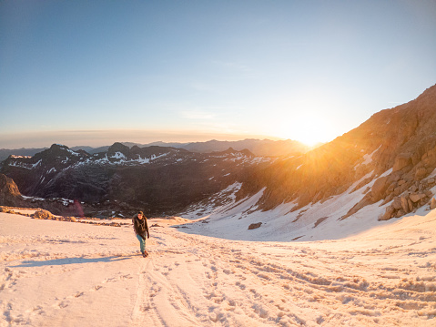 Dawn, alpinist moving on glacier to reach mountain peak at sunrise