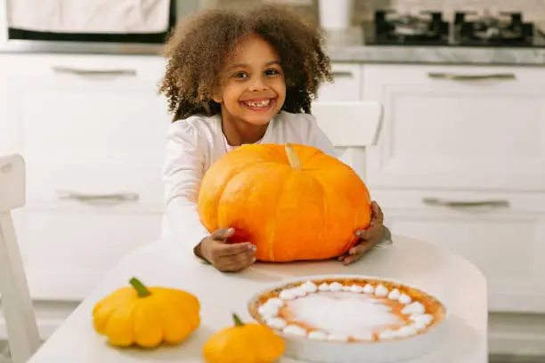 Photo of Child fool around with pumkin. Preparation for the Halloween party. Preparations for Thanksgiving day