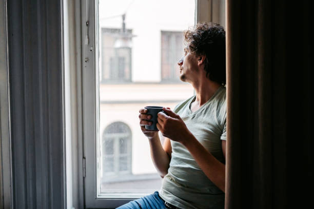 istock Young Man Drinking Coffee And Looking Out The Window 1432257519