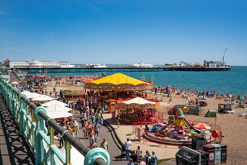 Brighton seafront seaside resort beach and Brighton Palace Pier in a summer sunny blue sky day with tourists in UK, Great Britain, England in East Sussex 47 miles south London, called as 