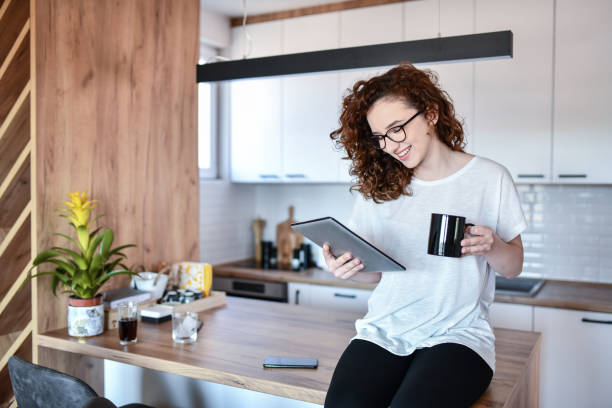 Female Reading Book On Digital Tablet During Coffee Time In Morning At Home