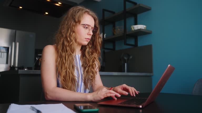 Camera slides around female freelancer's hands typing on laptop keyboard in slow motion. Business woman working at office with internet. Girl working remotely from home. Slider tracking shot.