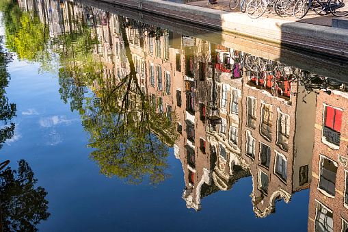 Traditional dutch canal houses in summer, seen in the reflections of the canal.