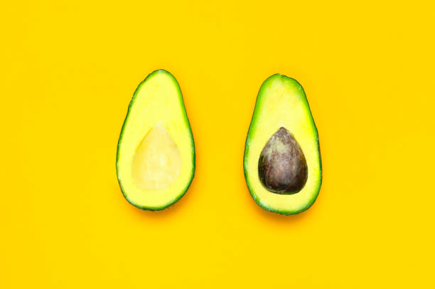 istock Ripe sliced avocado on bright yellow background top view. Creative food composition Flat lay. Pop art design, tropical summer abstract background with avocado. Green avocadoes pattern, diet concept 1432276806