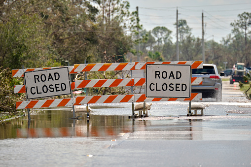 Road closed for roadworks and danger of flooding with warning signs blocking driving of cars.