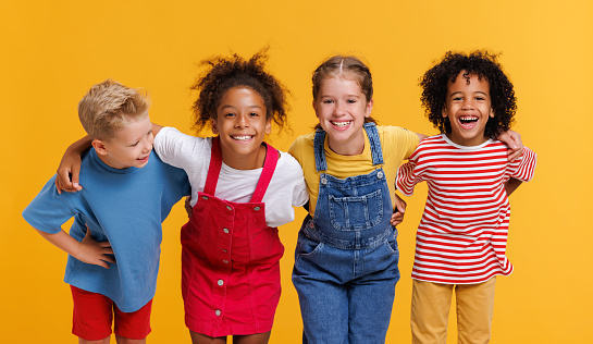 Group of cheerful happy multinational children on a colored yellow background