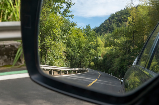 Mountain road in car rearview mirror