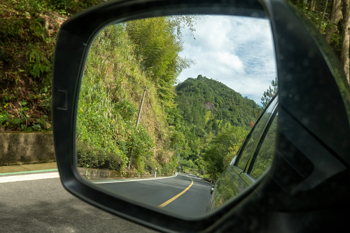 Mountain road in car rearview mirror