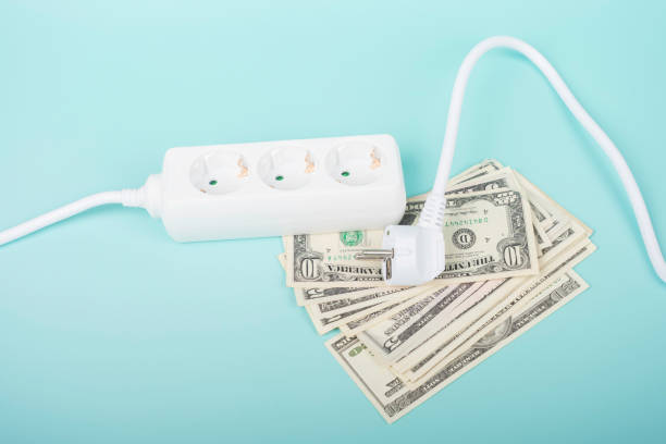 istock Electric power strip extension cord and US dollar bill banknotes on light blue background. Rising electric price and expensive energy concept 1432281643