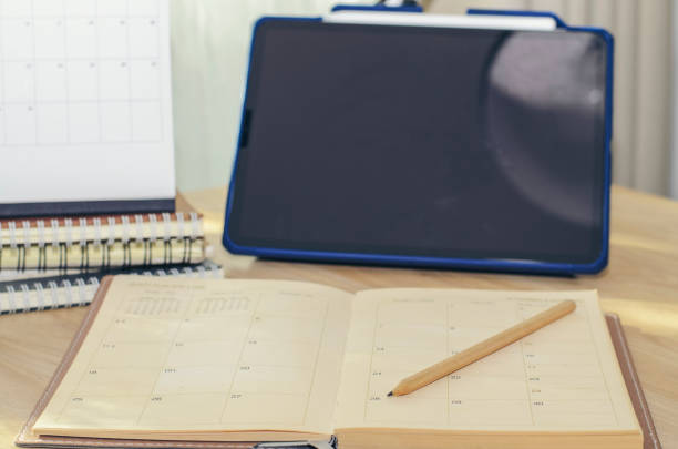 istock Diary, Calendar and agenda for Event Planner to plan timetable, appointment, organization, management on office table. Desktop Calender and tablet place on wooden desk. Calendar Background Concept 1432286881