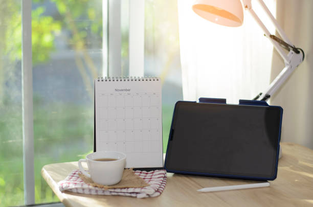 istock Desk for student concept. Tablet for study for exam, book place on School table for student work online at home. Desktop Calendar, notebook, book, cup of coffee , and Lamp place on wooden desk. 1432287029