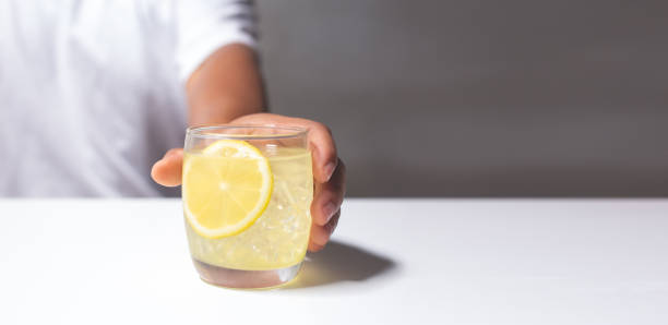 istock Man holding a glass of lemonade juice on white table. 1432287077
