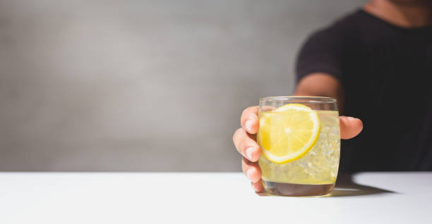 istock Man holding a glass of lemonade juice on white table. 1432287079