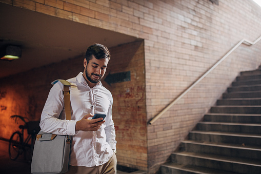 One man, modern young businessman using smart phone in underpass.