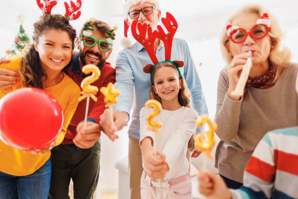 Family celebrating New Year holding balloons shaped as numbers 2023 stock photo