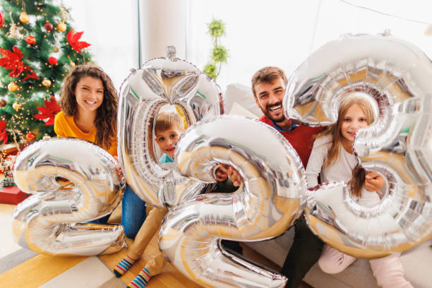 Family holding giant balloons shaped as numbers 2023 representing the upcoming New Year stock photo