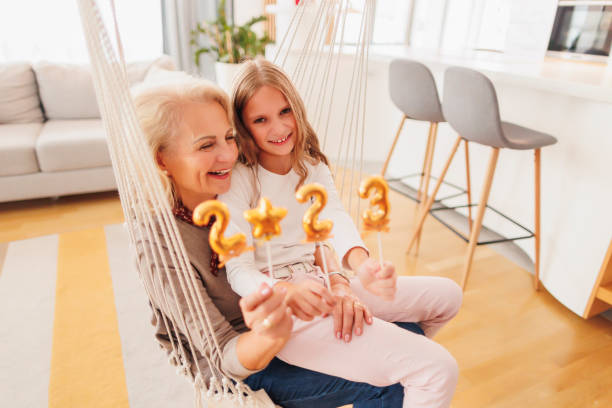 Grandmother and granddaughter holding balloons shaped as numbers 2023 stock photo
