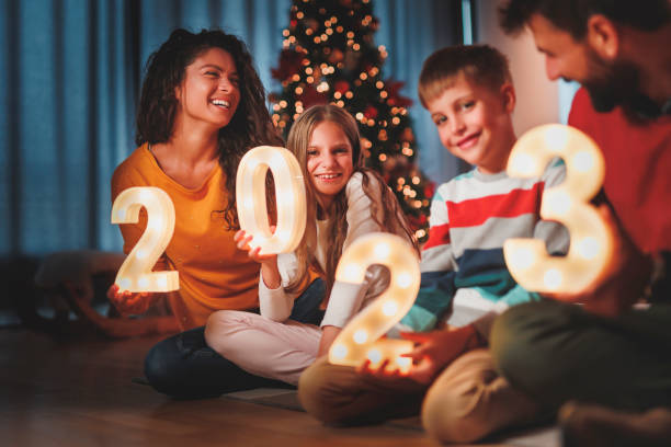 Parents and children holding illuminative numbers 2023 while celebrating New Year stock photo